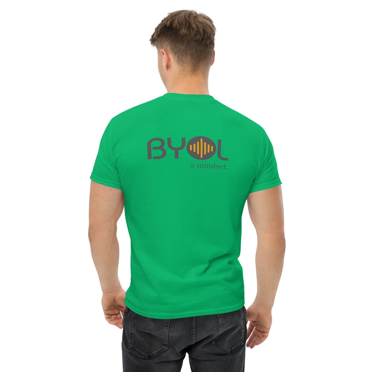 A young man with short blonde hair wearing a green "BYOL: a mindset" T-shirt, viewed from the back. The T-shirt features the "BYOL" logo in gray and yellow on the back and is available in multiple colors (maroon, black, brown, gold, plus more) and sizes (S-3XL). The "be you out loud" logo is displayed at the top.