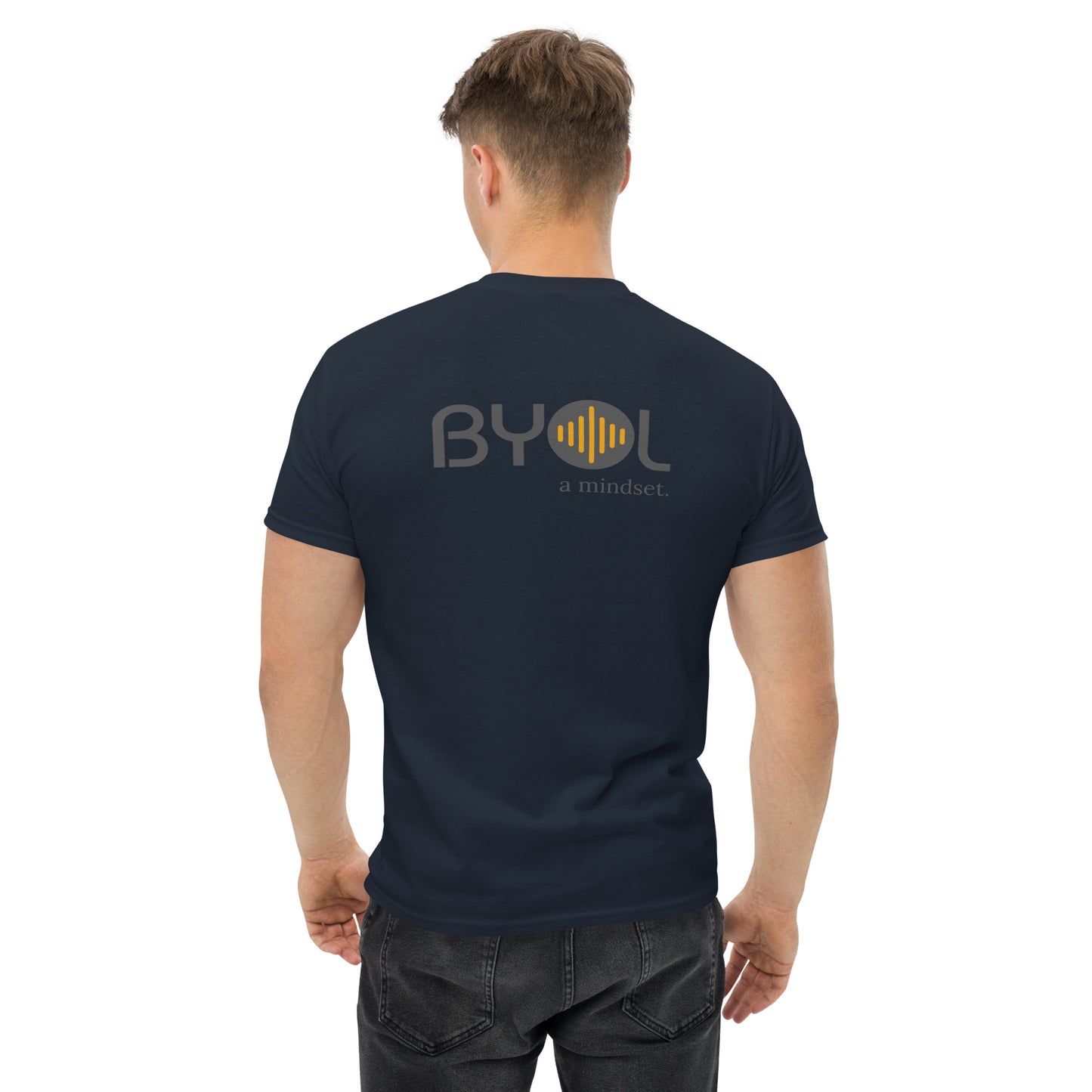 A young man with short blonde hair wearing a blue "BYOL: a mindset" T-shirt, viewed from the back. The T-shirt features the "BYOL" logo in gray and yellow on the back and is available in multiple colors (maroon, black, brown, gold, plus more) and sizes (S-3XL). The "be you out loud" logo is displayed at the top.