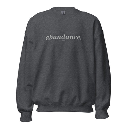 Dark heather sweatshirt with the phrase "abundance." printed on the front, available in color options navy blue, green, maroon, gray, and pink, available in sizes S to 3XL.