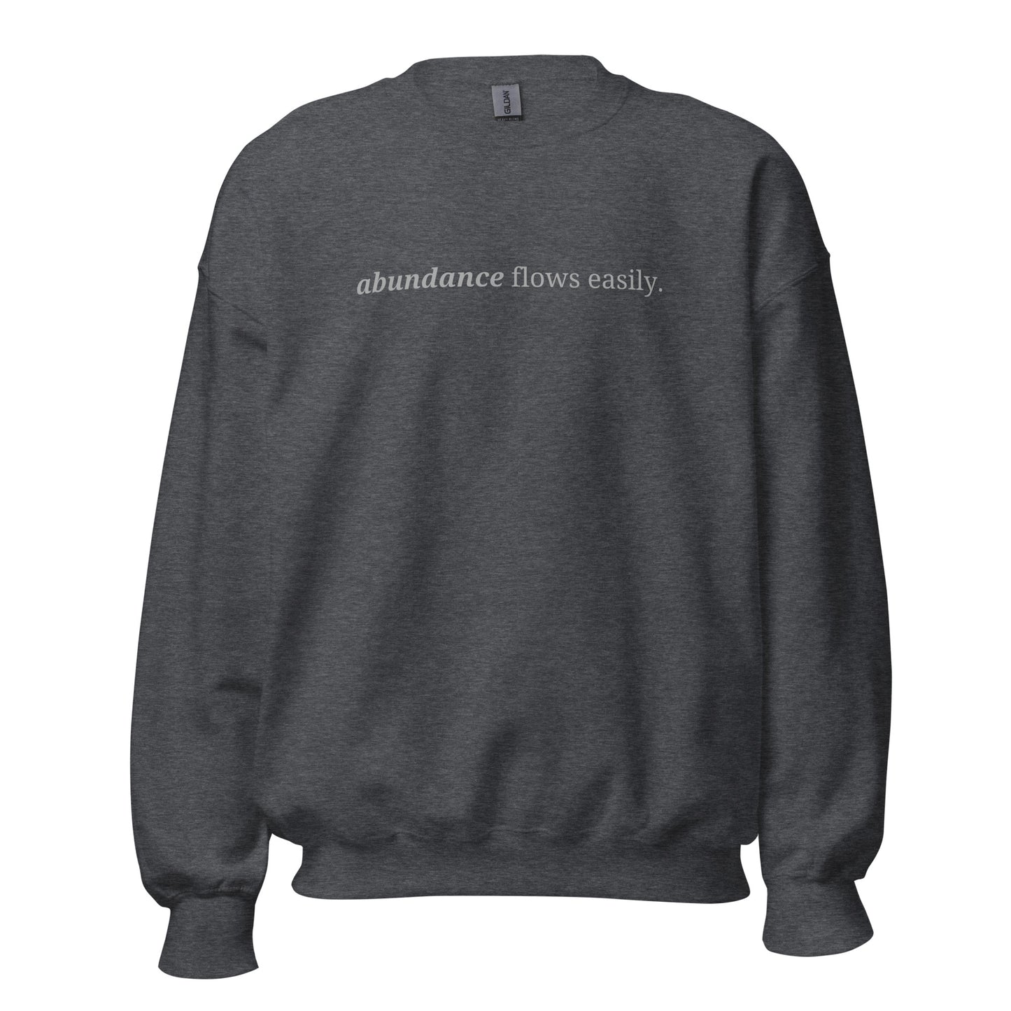 Dark heather grey sweatshirt with the phrase "abundance flows easily." printed on the front, available in color options navy blue, green, maroon, gray, and pink, available in sizes S to 3XL.