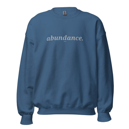 Indigo blue sweatshirt with the phrase "abundance." printed on the front, available in color options navy blue, green, maroon, gray, and pink, available in sizes S to 3XL.