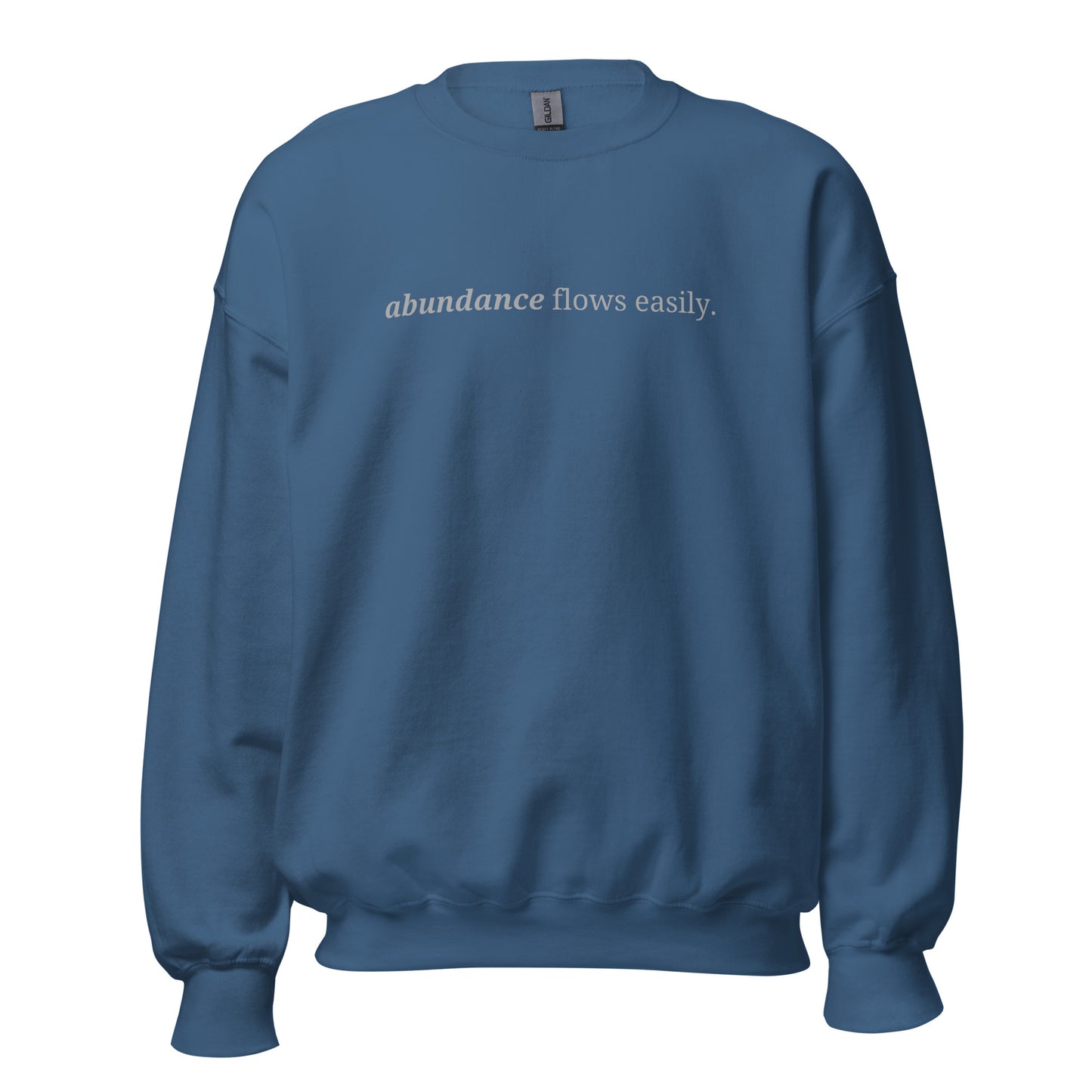 Indigo blue sweatshirt with the phrase "abundance flows easily." printed on the front, available in color options navy blue, green, maroon, gray, and pink, available in sizes S to 3XL.