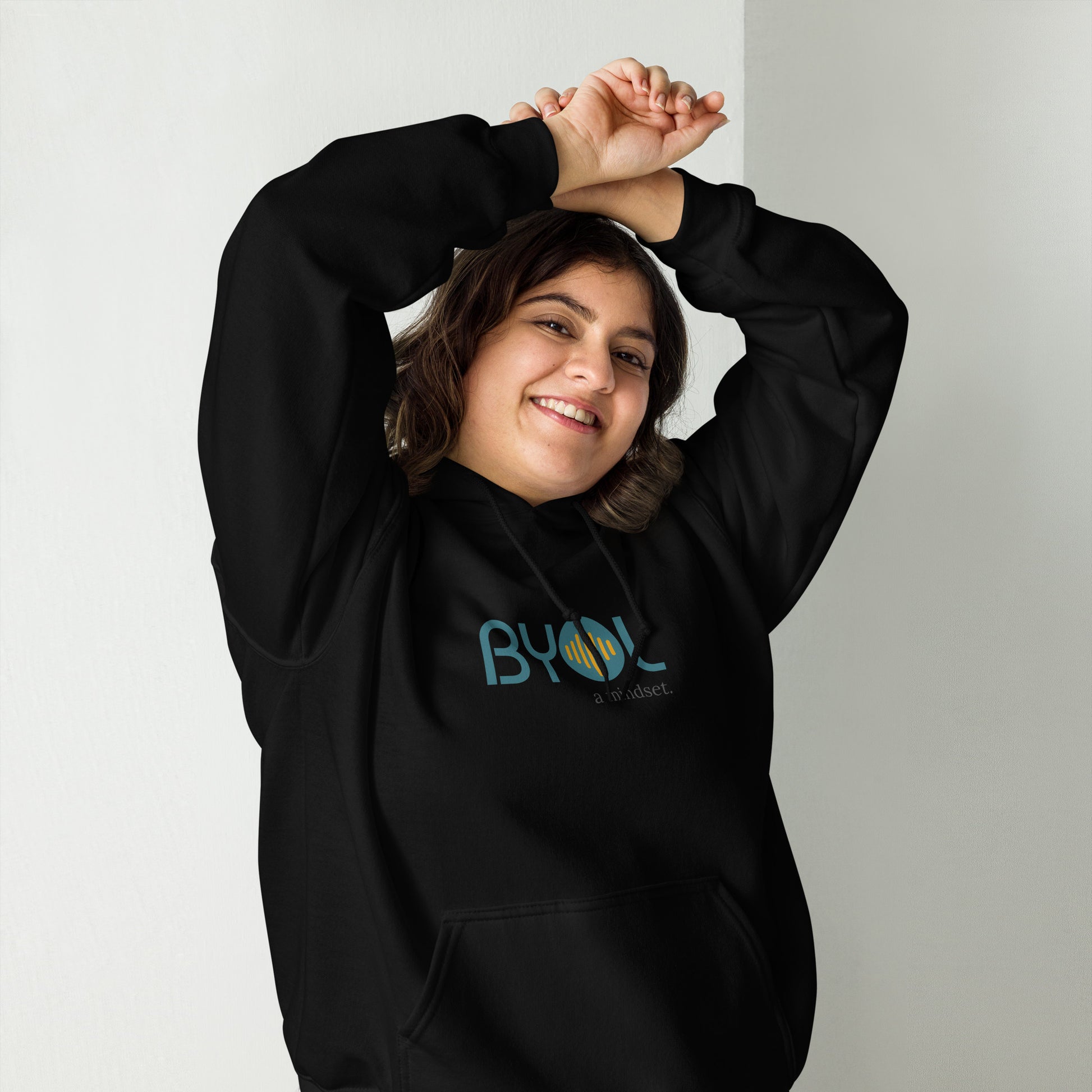 Woman wearing a black BYOL mindset hoodie with color options in black, maroon, olive green, and gray, available in sizes S to 5XL.