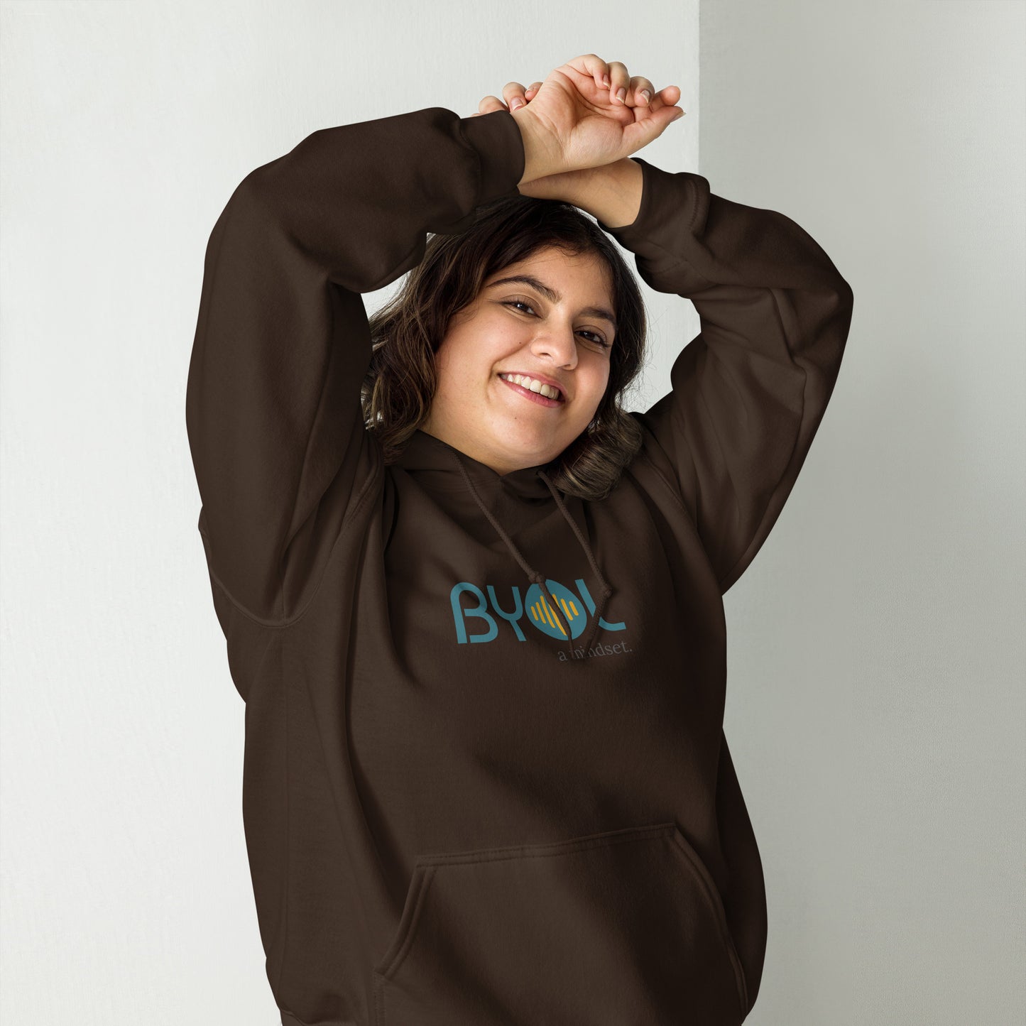 Woman wearing a dark chocolate BYOL mindset hoodie with color options in black, maroon, olive green, and gray, available in sizes S to 5XL.