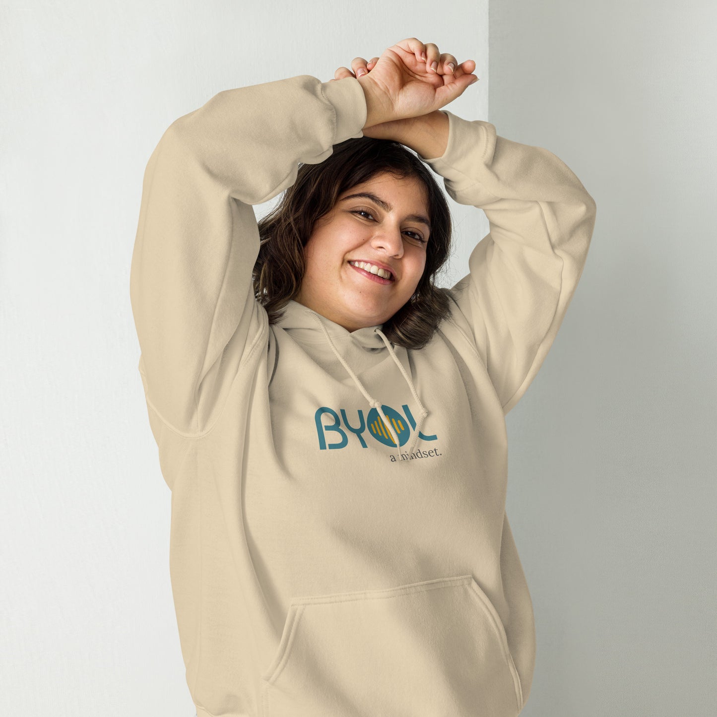 Woman wearing a sand BYOL mindset hoodie with color options in black, maroon, olive green, and gray, available in sizes S to 5XL.