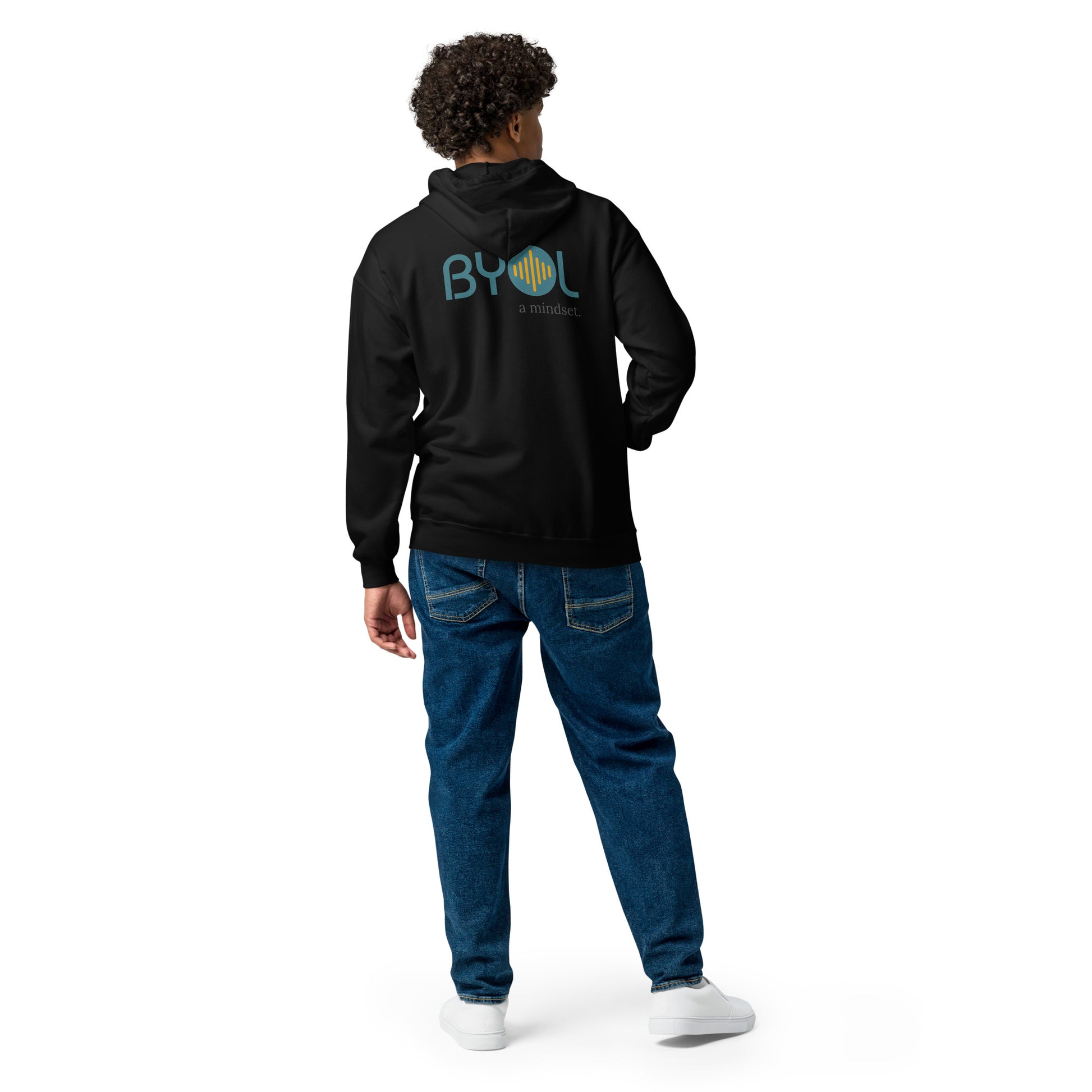 A young man with curly hair wearing a black "BYOL: a mindset" hoodie, viewed from the back. The hoodie features the "BYOL" logo in teal and yellow on the back and is available in multiple colors (black, gray, navy, white, plus more) and sizes (S-3XL). The "be you out loud" logo is displayed at the top.