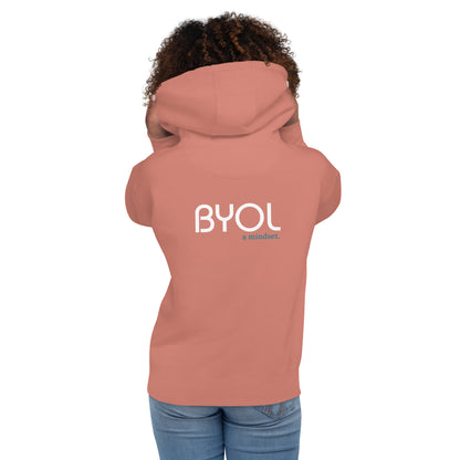 Back view of a woman wearing a dusty pink BYOL mindset hoodie with color options in black, maroon, dark gray, and light pink, available in sizes S to 3XL.