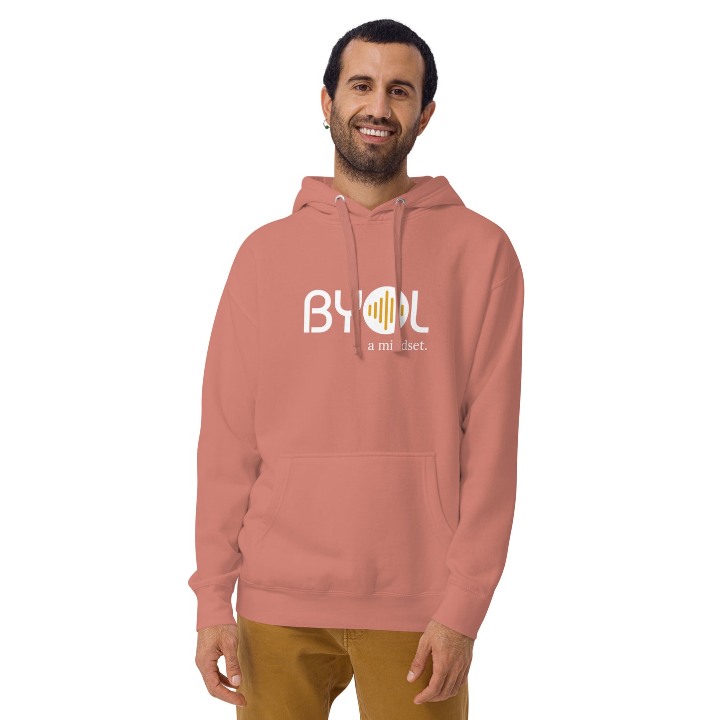 A young man with short hair and a beard wearing a dusty rose "BYOL: a mindset" hoodie, smiling and standing with his arms at his sides. The hoodie features the "BYOL" logo in white and yellow on the front and is available in multiple colors (black, dark gray, maroon, pink, light gray, plus more) and sizes (S-3XL). The "be you out loud" logo is displayed at the top.