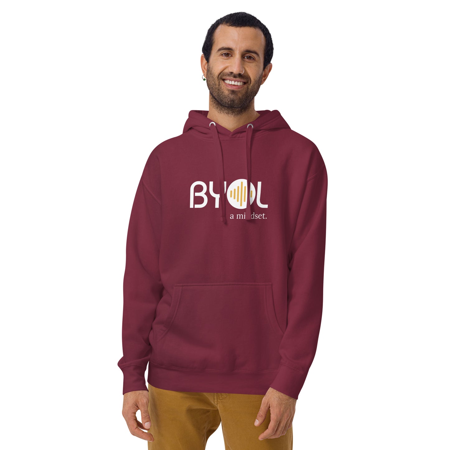 A young man with short hair and a beard wearing a maroon "BYOL: a mindset" hoodie, smiling and standing with his arms at his sides. The hoodie features the "BYOL" logo in white and yellow on the front and is available in multiple colors (black, dark gray, maroon, pink, light gray, plus more) and sizes (S-3XL). The "be you out loud" logo is displayed at the top.