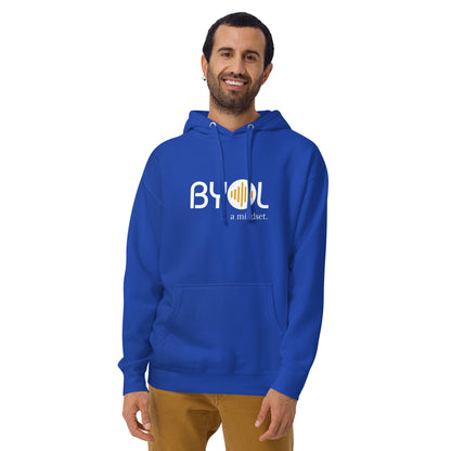 A young man with short hair and a beard wearing a royal blue "BYOL: a mindset" hoodie, smiling and standing with his arms at his sides. The hoodie features the "BYOL" logo in white and yellow on the front and is available in multiple colors (black, dark gray, maroon, pink, light gray, plus more) and sizes (S-3XL). The "be you out loud" logo is displayed at the top.