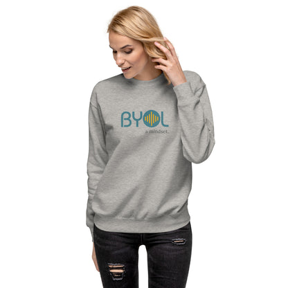 Woman wearing a carbon grey BYOL mindset sweatshirt with color options in black, dark gray, pink, and light gray, available in sizes S to 2XL.