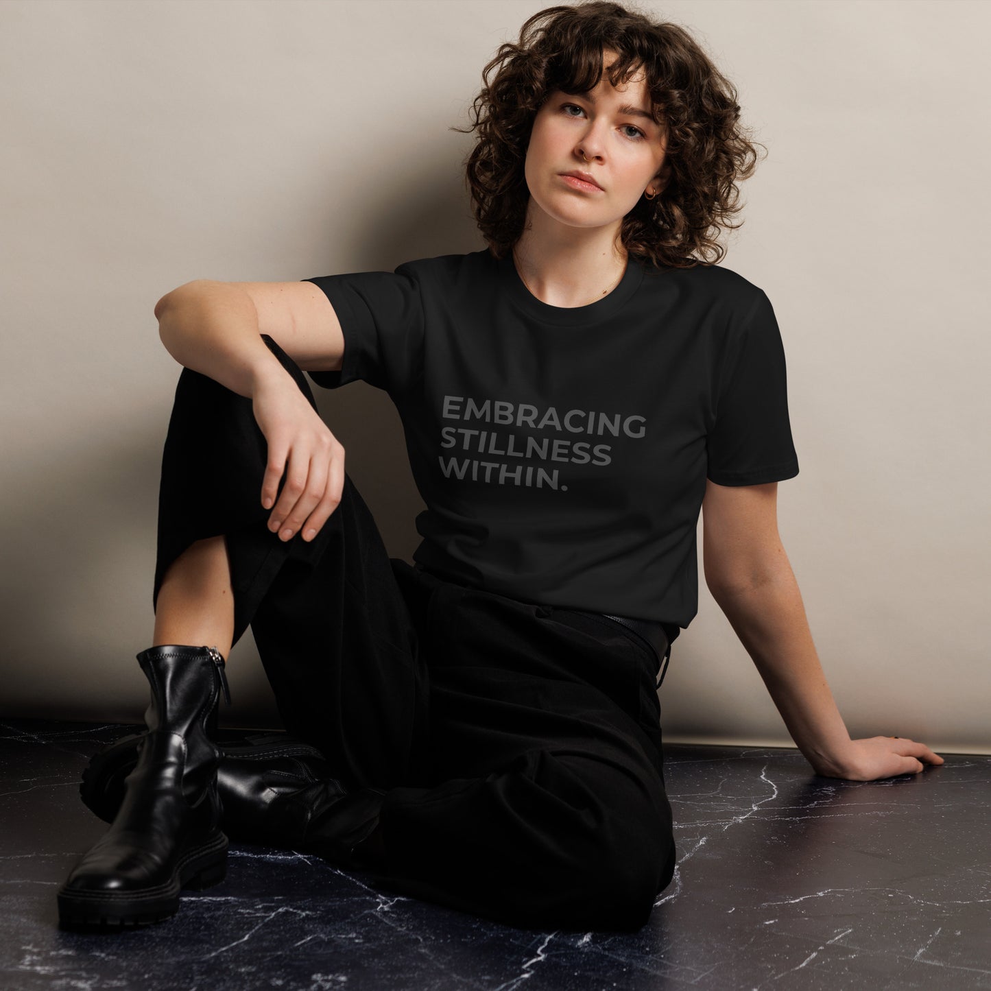 Woman wearing a black premium tee with "Embracing Stillness Within" text.