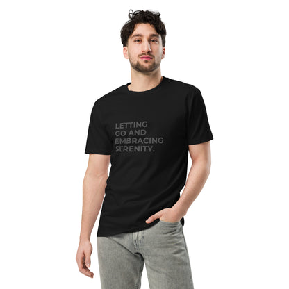 Man wearing a black premium tee with the text "Letting Go and Embracing Serenity".