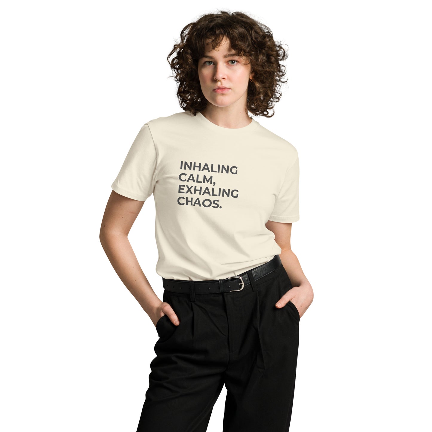 Woman wearing a natural premium tee with "Inhaling Calm, Exhaling Chaos" text.