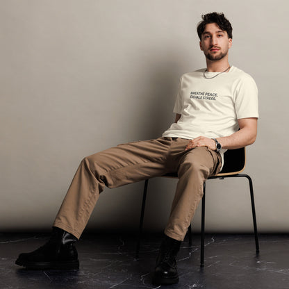 Man sitting wearing a natural premium tee with the text "Breathe Peace, Exhale Stress".