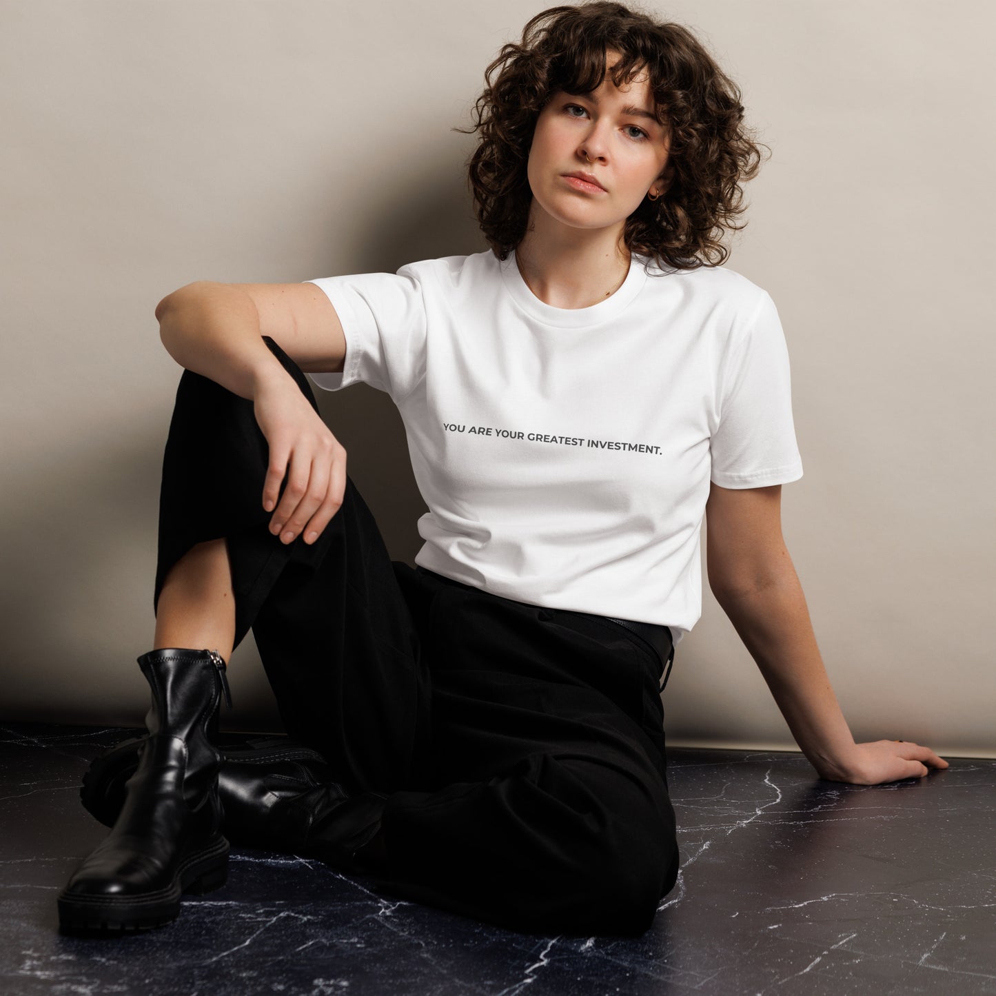 Woman wearing a white premium tee with "You Are Your Greatest Investment" text.