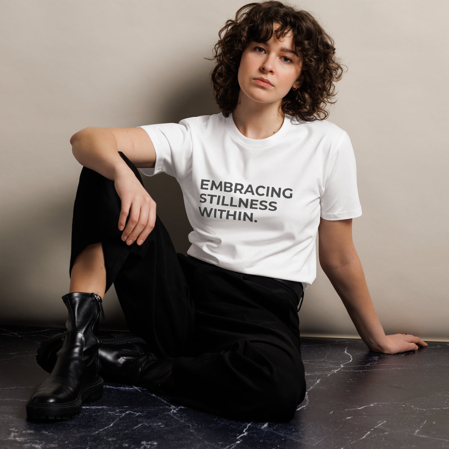 Woman wearing a white premium tee with "Embracing Stillness Within" text.