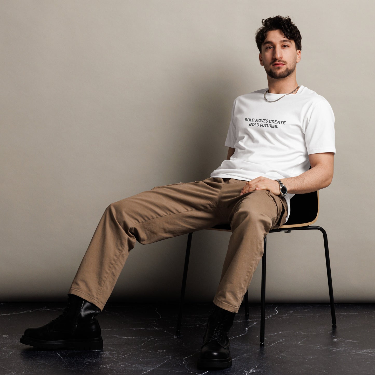 Man sitting wearing a white premium tee with the text "Bold Moves Create Bold Futures".