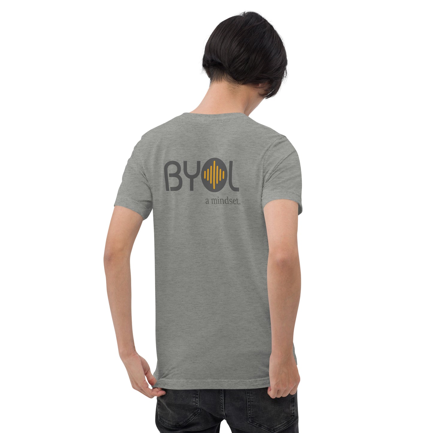 A young man with short black hair wearing a grey tri-blend "BYOL: a mindset" T-shirt, viewed from the back. The T-shirt features the "BYOL" logo in black and yellow on the back and is available in multiple colors (black, red, gray, pink, gold, plus more) and sizes (S-3XL). The "be you out loud" logo is displayed at the top.