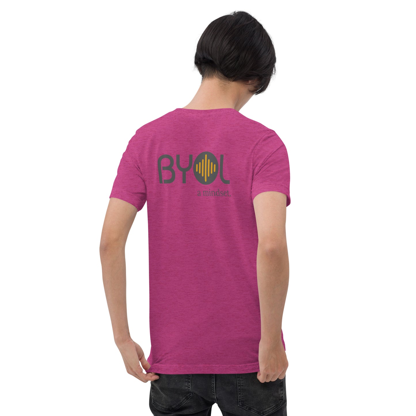 A young man with short black hair wearing a pink tri-blend "BYOL: a mindset" T-shirt, viewed from the back. The T-shirt features the "BYOL" logo in black and yellow on the back and is available in multiple colors (black, red, gray, pink, gold, plus more) and sizes (S-3XL). The "be you out loud" logo is displayed at the top.