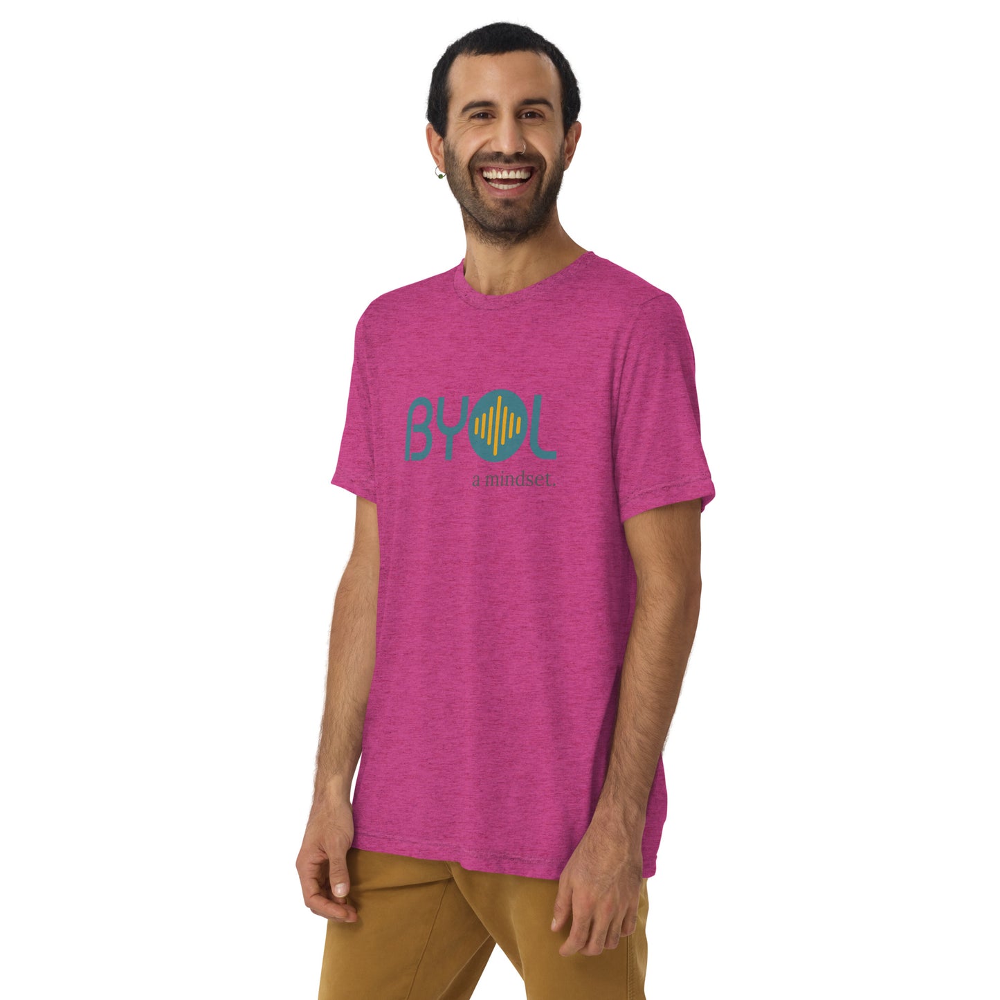 A young man with short dark hair and a beard wearing a berry tri-blend "BYOL: a mindset" T-shirt, smiling and standing with his arms at his sides. The T-shirt features the "BYOL" logo in teal and is available in multiple colors (black, red, gray, pink, yellow, plus more) and sizes (S-3XL). The "be you out loud" logo is displayed at the top.