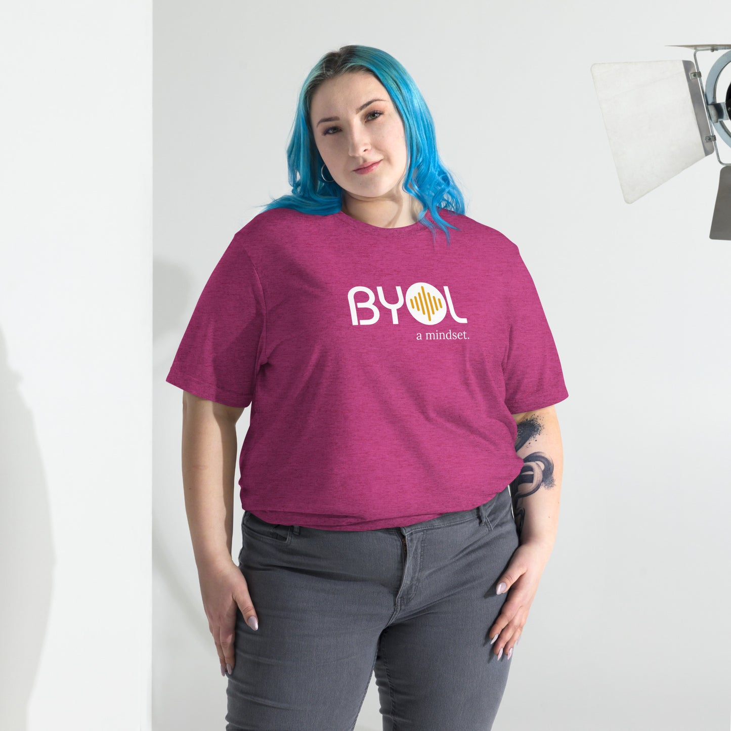 Woman wearing a loose fit BYOL mindset t-shirt in berry triblend with color options in black, red, pink, gray, and yellow, available in sizes S to 3XL.