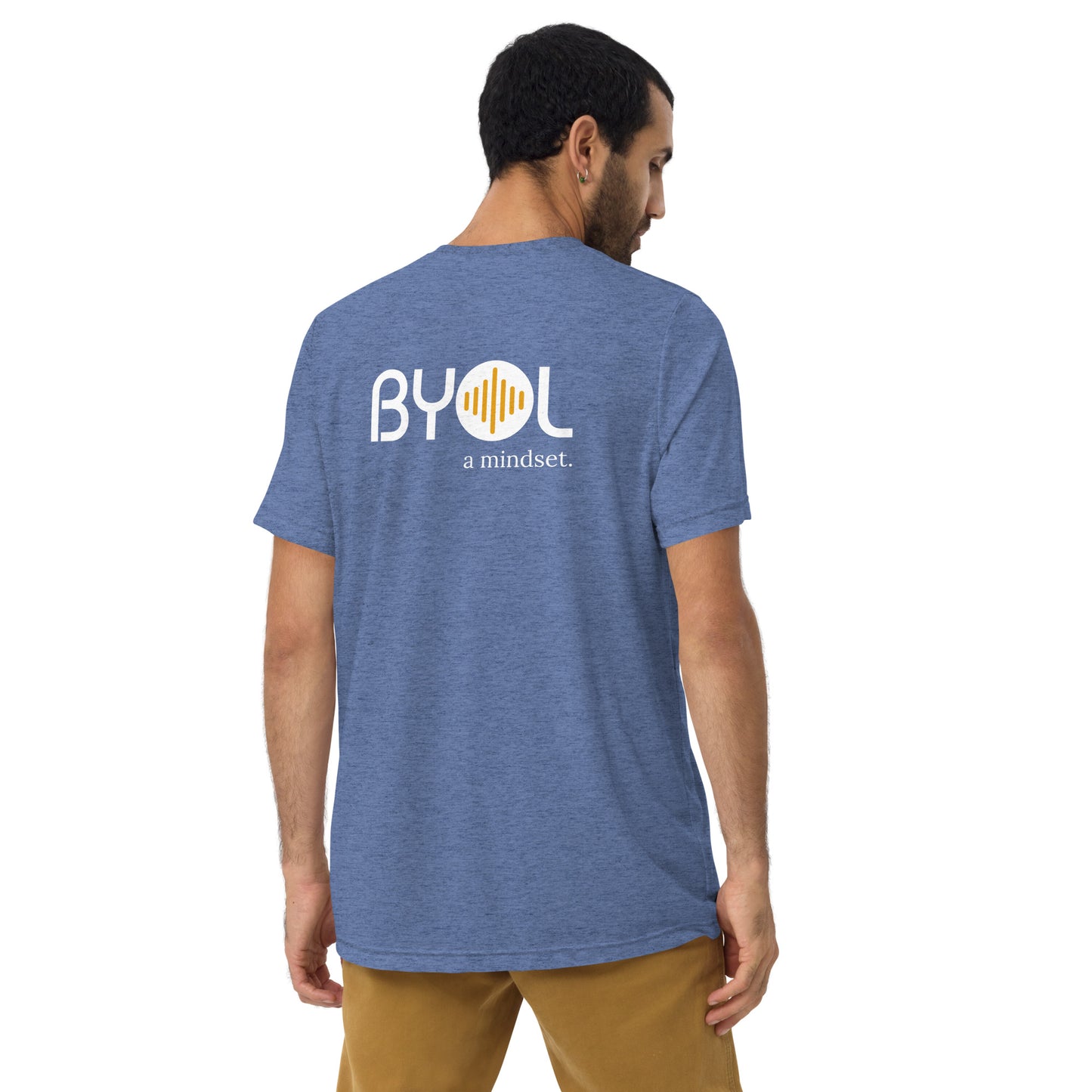 A young man with short dark hair wearing a blue tri-blend "BYOL: a mindset" T-shirt, viewed from the back. The T-shirt features the "BYOL" logo in white and yellow on the back and is available in multiple colors (black, red, gray, pink, beige, plus more) and sizes (S-3XL). The "be you out loud" logo is displayed at the top.