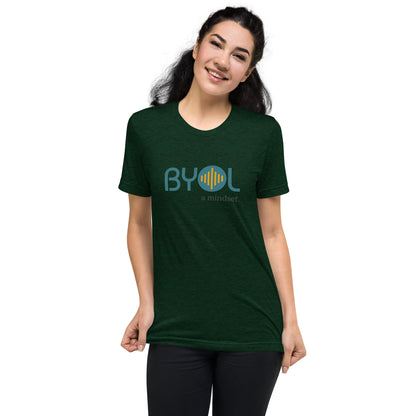 Woman wearing a emerald triblend BYOL mindset t-shirt with color options in black, red, pink, gray, and yellow, available in sizes S to 3XL.