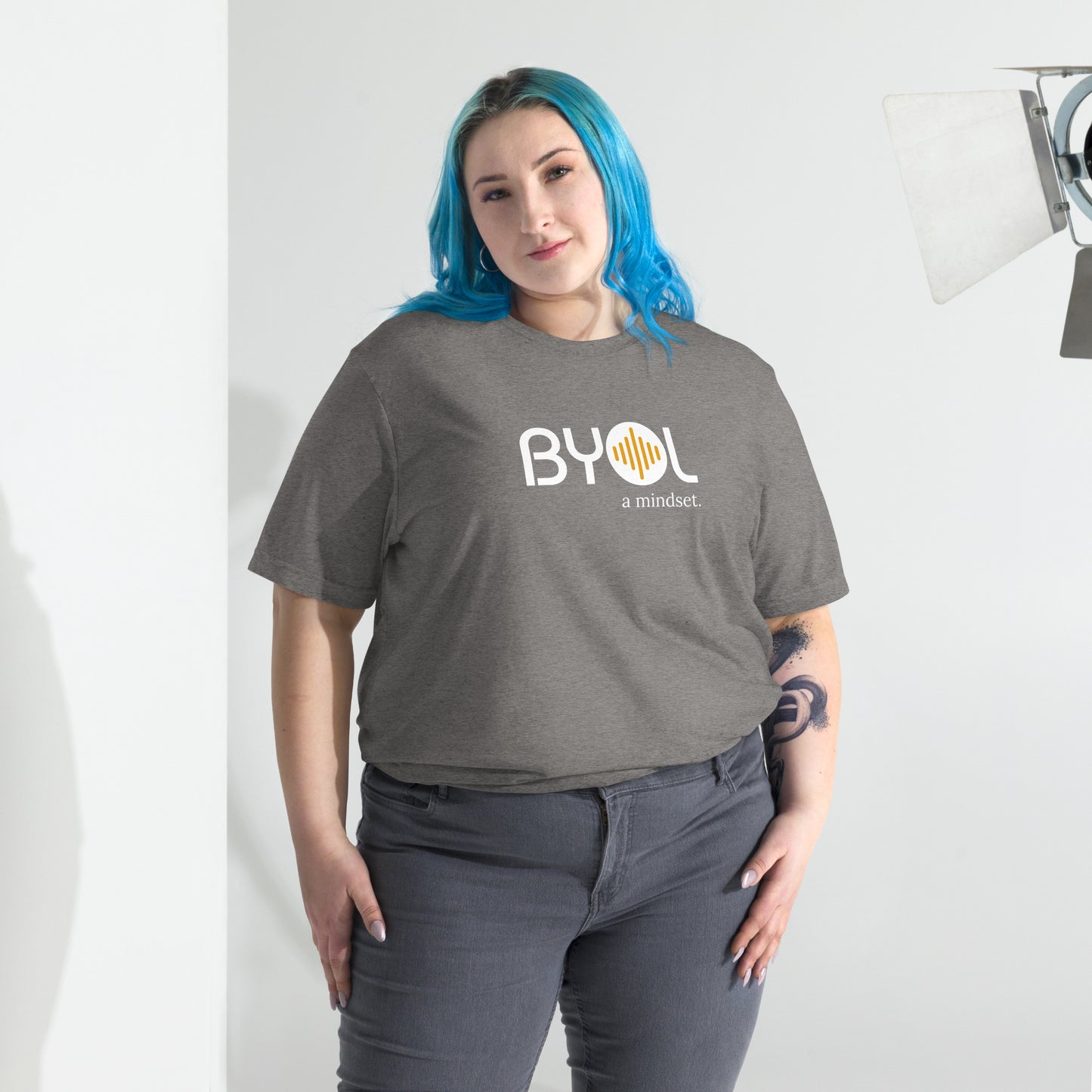 Woman wearing a loose fit BYOL mindset t-shirt in grey triblend with color options in black, red, pink, gray, and yellow, available in sizes S to 3XL.