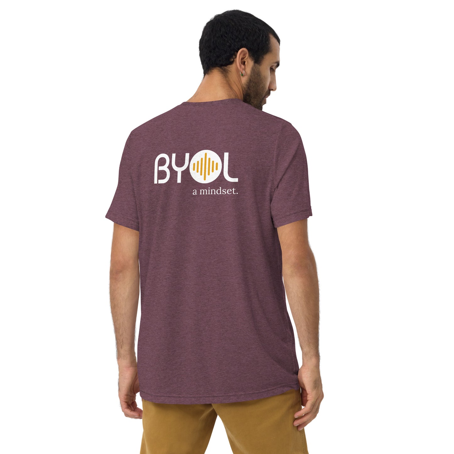 A young man with short dark hair wearing a maroon tri-blend "BYOL: a mindset" T-shirt, viewed from the back. The T-shirt features the "BYOL" logo in white and yellow on the back and is available in multiple colors (black, red, gray, pink, beige, plus more) and sizes (S-3XL). The "be you out loud" logo is displayed at the top.