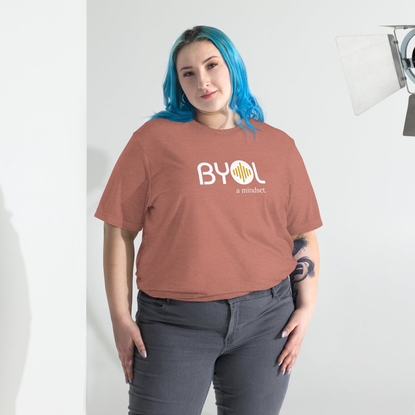 Woman wearing a loose fit BYOL mindset t-shirt in mauve triblend with color options in black, red, pink, gray, and yellow, available in sizes S to 3XL.