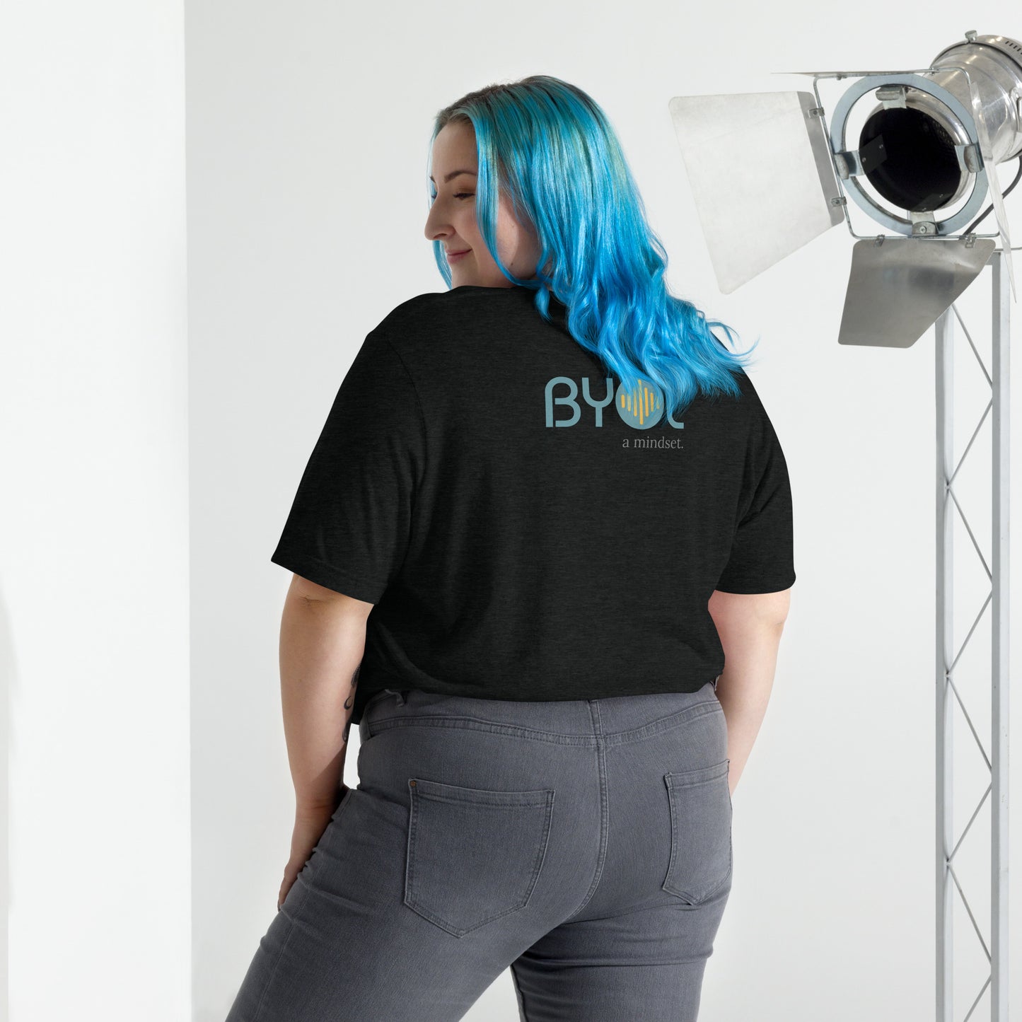 Back view of a woman wearing a black tri-blend BYOL mindset t-shirt with color options in black, red, pink, gray, and yellow, available in sizes S to 3XL.