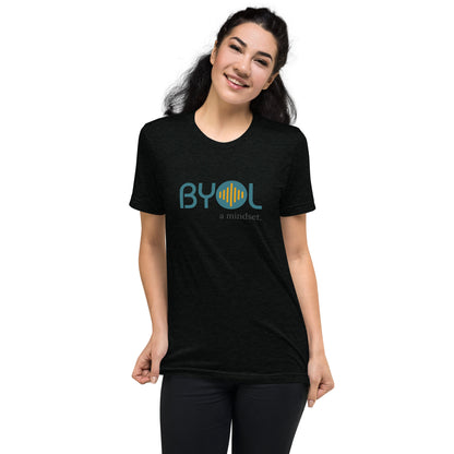 Woman wearing a black triblend BYOL mindset t-shirt with color options in black, red, pink, gray, and yellow, available in sizes S to 3XL.