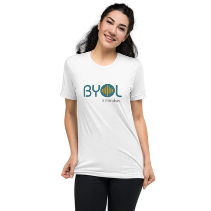 Woman wearing a solid white BYOL mindset t-shirt with color options in black, red, pink, gray, and yellow, available in sizes S to 3XL.