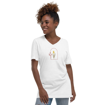 Woman wearing a white V-neck tee with a floral archway design, representing subtle elegance and authenticity.