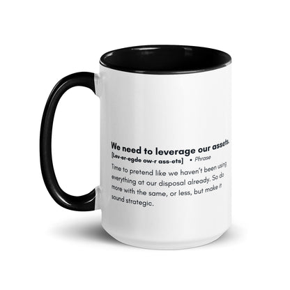 White ceramic mug with black inside and handle with the words, "We need to leverage our assets" followed by a humorous definition. 