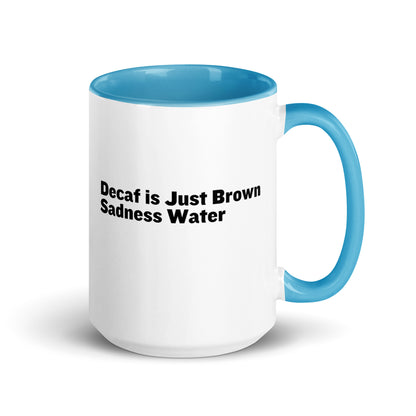 White ceramic mug with a light blue inside and handle with the words, "Decaf is just Brown Sadness water"