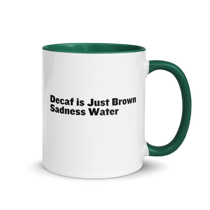 White ceramic mug with a green inside and handle with the words, "Decaf is just Brown Sadness water"