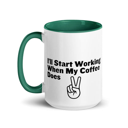 White ceramic mug with a green inside and handle with the words, "I'll start working when my coffee does"