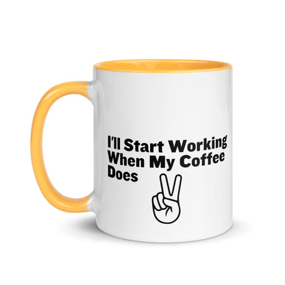 White ceramic mug with a golden yellow inside and handle with the words, "I'll start working when my coffee does"