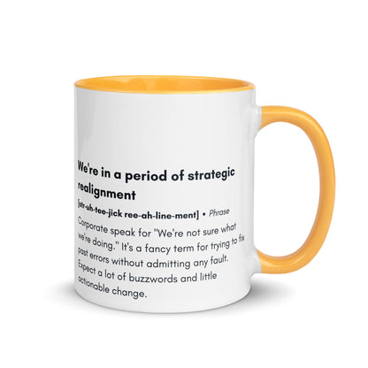 ceramic white mug with dark yellow inside and handle with the words "we're in a period of strategic realignment" with a humorous definition. 