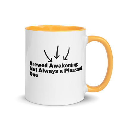 White ceramic mug with golden yellow on the inside and on the handle with the words, "Brewed awakening: Not always a pleasant one