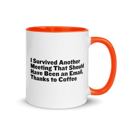 White ceramic mug with orange inside and on the handle with words that say, "I survived another meeting that should have been an email, thanks to coffee"