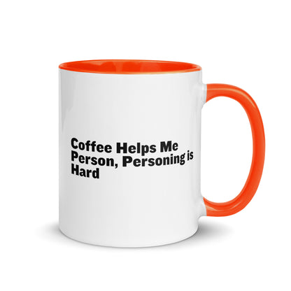 White ceramic mug with orange inside and on the handle with the words, "Coffee helps me person, personing is hard"