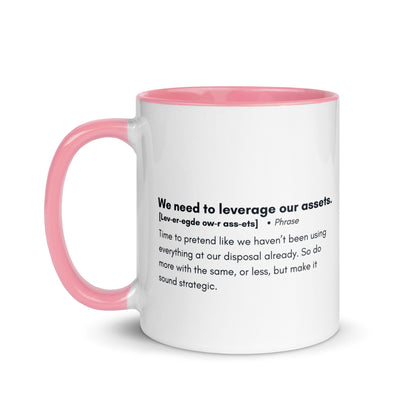 White ceramic mug with pink inside and handle with the words, "We need to leverage our assets" followed by a humorous definition.