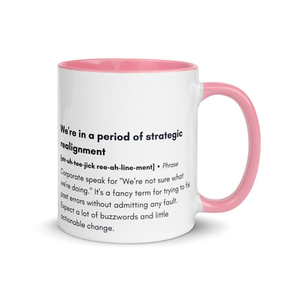 ceramic white mug with pink inside and handle with the words "we're in a period of strategic realignment" with a humorous definition. 