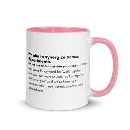 White ceramic mug with light pink inside and handle with word,"We aim to synergize across departments" followed by a humorous definition.