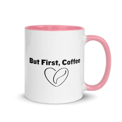 White ceramic mug with pink on the inside and on the handle with words that say, "But first, coffee"