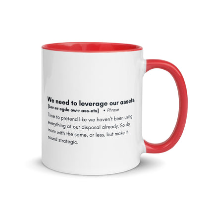 White ceramic mug with red inside and handle with the words, "We need to leverage our assets" followed by a humorous definition. 