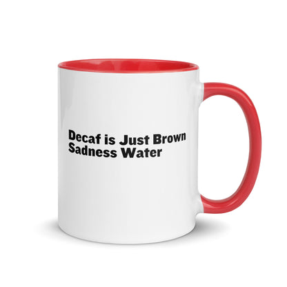 White ceramic mug with a red inside and handle with the words, "Decaf is just Brown Sadness water"